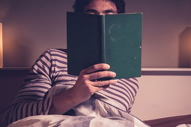 Person entspannt beim Lesen im Bett