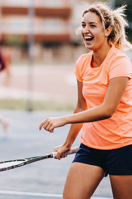 Junge Frau spielt lächelnd Tennis